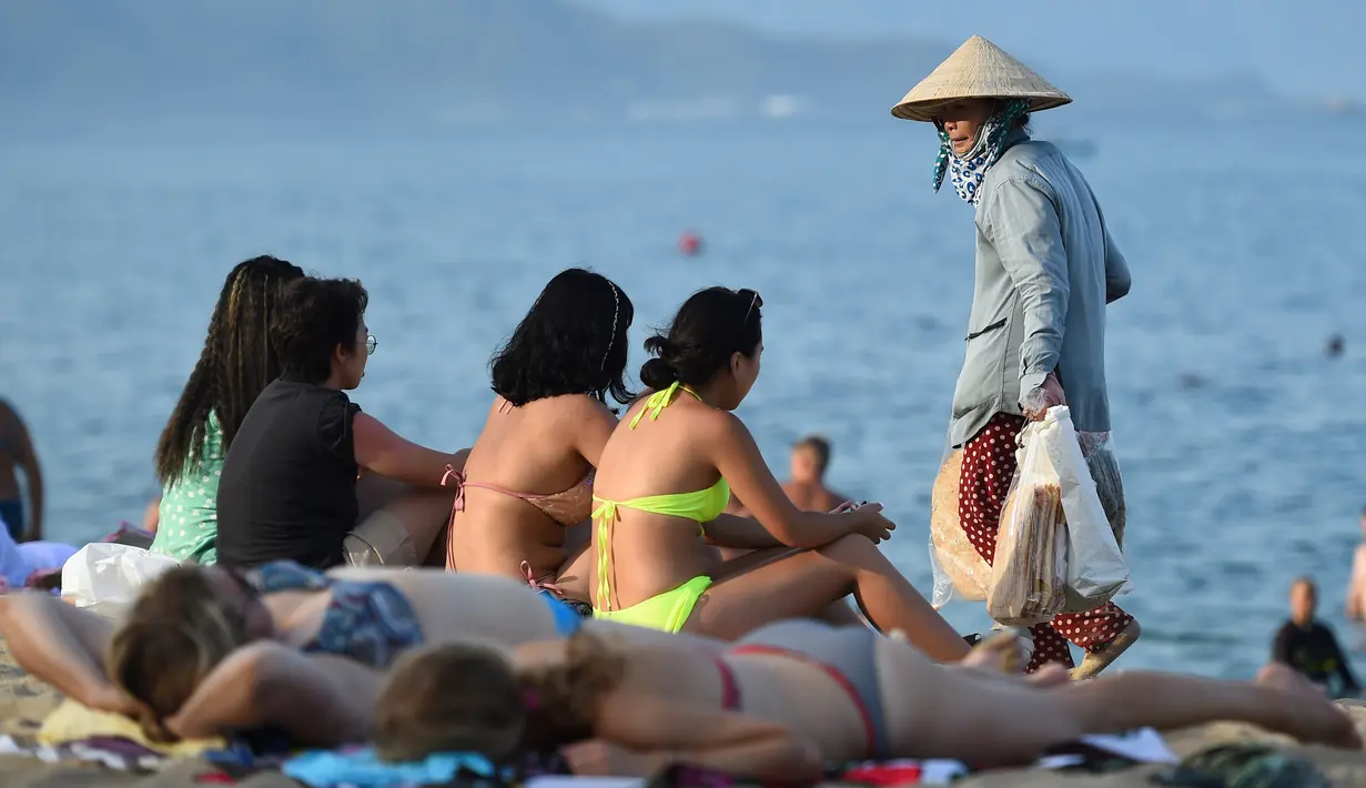 Sejumlah turis bersantai sambil menikmati pantai Nha Trang di provinsi Khanh Hoa (21/8/2019). Di dekat pantai, terdapat taman yang tertata rapi dan banyak digunakan oleh penduduk kota tersebut untuk berolahraga. (AFP Photo/Nhac Nguyen)