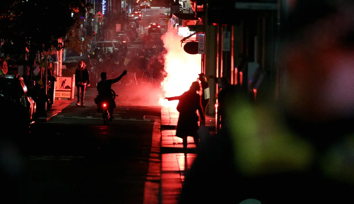 Pengunjuk rasa menyalakan suar saat memprotes perpanjangan lockdown atau penguncian ketat di Melbourne, Australia, Kamis (5/8/2021). Pemerintah Australia kembali memperpanjang lockdown di Melbourne selama sepekan untuk menekan penyebaran virus corona Covid-19 varian delta. (AFP/Con Chroinis)