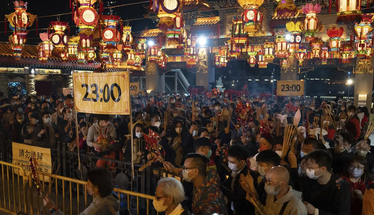 Warga yang mengenakan maskerantre untuk membakar dupa pertama mereka di Kuil Wong Tai Sin untuk merayakan Tahun Baru Imlek yang menandai Tahun Kelinci, di Hong Kong, Sabtu, 21 Januari 2023. Tahun lalu dan tahun sebelumnya orang-orang tidak boleh berkunjung karena pembatasan COVID-19. (AP Photo/Bertha Wang)