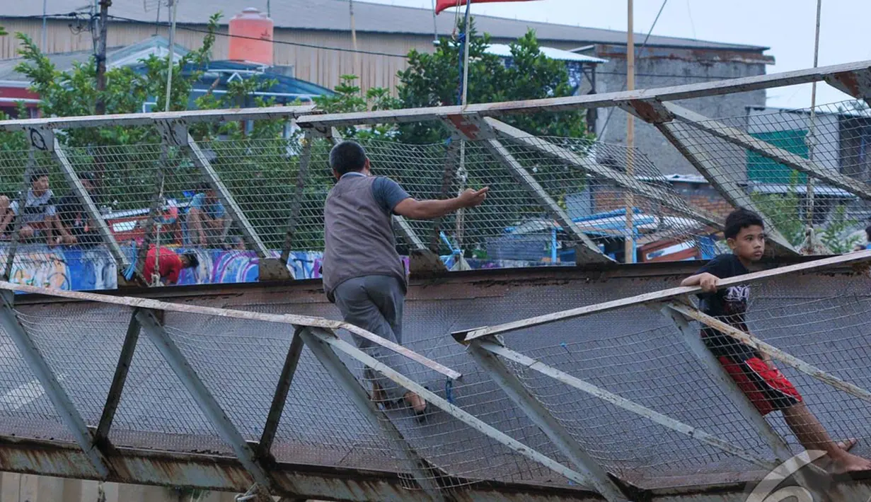 Warga nekat melintas di Jembatan Gantung yang rusak di Petamburan, Jakarta Barat, Sabtu (14/06) (Liputan6.com/Andrian M Tunay)