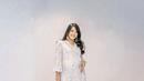 Anggun dan berkelas, Anissa mengenakan midi dress bernuansa putih dengan motif kembang. Handbag putih dipilih sebagai paduannya. (Instagram/anissaaziza).