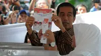 Jokowi yang mengenakan baju batik tampak menunjukkan surat suara yang akan dicoblos ke puluhan awak media, Jakarta, Rabu (9/7/14). (Liputan6.com/Herman Zakharia)