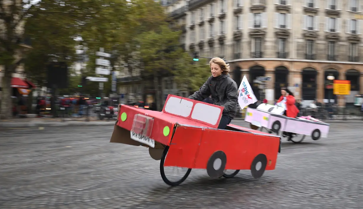 Sejumlah orang naik sepeda yang dihias kardus berbentuk mobil di Place de la Bastille, Paris, Prancis (1/10). Acara hari bebas kendaraan bermotor yang digelar pada 1 Oktober ini merupakan yang ketiga kalinya. (AFP Photo/Eric Feferberg)