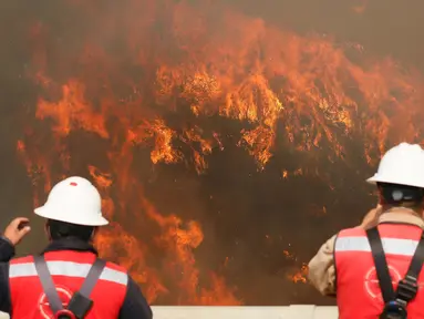 Dua orang petugas melihat kebakaran besar yang melanda kota pantai Valparaiso di Chile, Senin (2/1). Api menghanguskan sedikitnya 100 rumah dan mendorong evakuasi pada sekitar 400 orang. (REUTERS/Rodrigo Garrido)