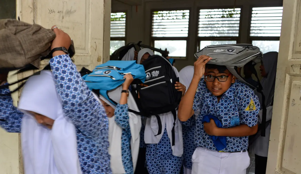 Sejumlah siswa berlarian menyelamatkan diri saat simulasi bencana gempa dan tsunami di sebuah sekolah di Banda Aceh, Aceh, Rabu (9/10/2019). Para siswa dibekali wawasan tanggap darurat bencana dan pemberian pertolongan pertama pada korban gempa. (Photo by CHAIDEER MAHYUDDIN / AFP)