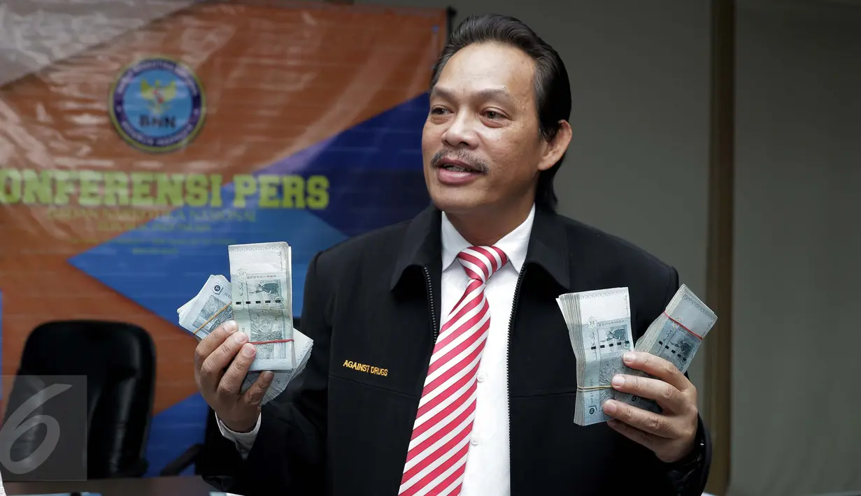 Deputi Pemberantasan Narkotika, Irjen Pol Arman Depari menunjukan barang bukti beserta tersangka saat rilis kasus tindak pencucian uang di BNN, Jakarta, Kamis (24/11). BNN menyita aset senilai Rp 153 Miliar dari tersangka MI. (Liputan6.com/Gempur M Surya)