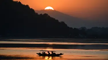 Nelayan menunggu di perahu kecil setelah memancing di Danau Dal saat matahari terbenam di Srinagar (9/9/2019). Danau Dal dijuluki sebagai Jewel in the Crown of Kashmir atau Srinagar Jewel. (AFP Photo/Tauseef Mustafa)