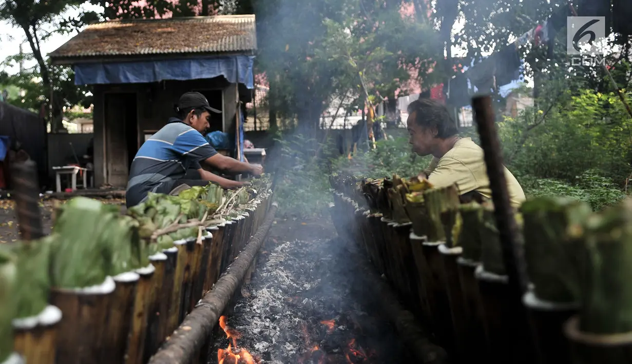 Pak Pian ditemani Pak Bambang saat memasak lemang di sebuah tanah kosong di Jakarta, Minggu (27/5). Memasuki bulan Ramadan, produksi makanan tradisional Melayu berbahan dasar ketan tersebut terus meningkat. (Merdeka.com/Iqbal S Nugroho)