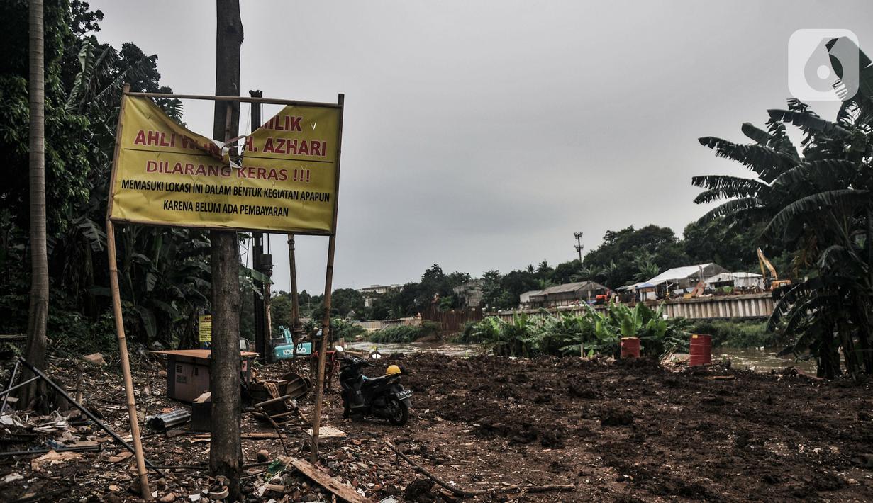 Sebuah spanduk penolakan ahli waris berada di sekitar proyek pembangunan saringan sampah Kali Ciliwung segmen Jalan TB Simatupang, Jakarta, Minggu (12/2/2023). Diketahui, total lahan yang belum dibebaskan di area saringan sampah TB Simatupang seluas 3.197 meter persegi yang dimiliki oleh 3 pihak. Total anggaran yang disiapkan untuk membebaskan lahan sebesar Rp24 miliar. (merdeka.com/Iqbal S Nugroho)