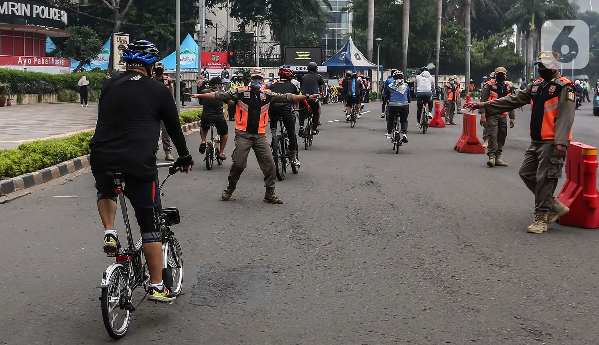 Satpol PP menghentikan pesepeda yang tidak mengenakan masker dengan benar di kawasan Bundaran HI, Jakarta, Minggu (17/1/2021). Pemerintah terus melakukan berbagai upaya guna mencegah penyebaran COVID-19 dan menurunkan angka masyarakat yang terpapar virus corona. (Liputan6.com/Johan Tallo)