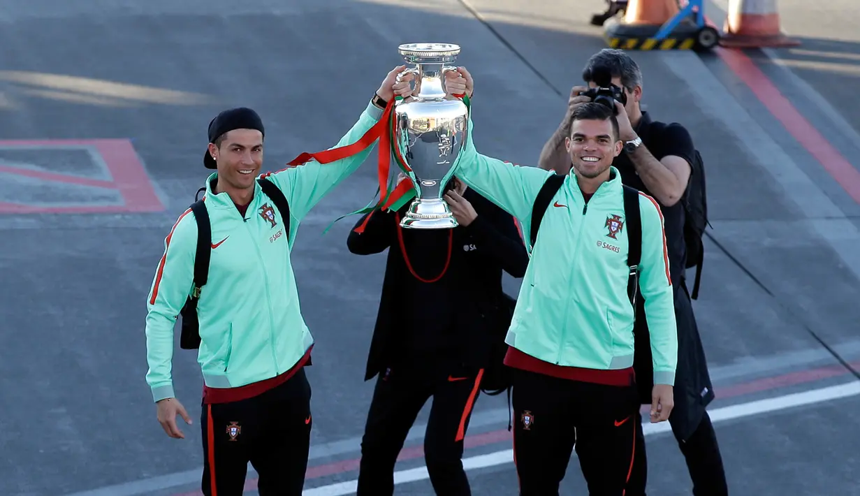 Pemain sepak bola Portugal Cristiano Ronaldo dan Pepe berpose sambil menunjukan trofi Euro 2016 saat mereka berada di bandara Medeira, Portugal (27/3). (AP Photo/Armando Franca)