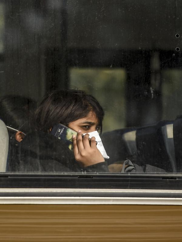 Seorang wanita India berada di dalam bus saat keluar dari Bandara Internasional Indira Gandhi setelah dievakuasi dari kota Wuhan di China, di New Delhi (1/2/2020). Jumlah total kematian akibat wabah virus corona di China tercatat mencapai 259 hingga Jumat (31/1/2020). (AFP/Money Sharma)