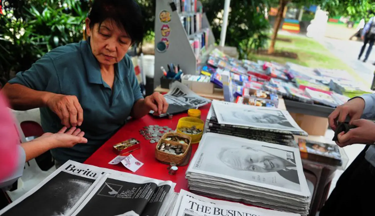 Warga membeli surat kabar setelah sehari meninggalnya mantan PM Singapura, Lee Kuan Yew, Singapura, Selasa (24/3/2015). Lee meninggal pada hari Senin (23/3) di usia 91 tahun dan wajahnya menghiasi berbagai media cetak Singapura. (AFP PHOTO/Mohd FYROL)