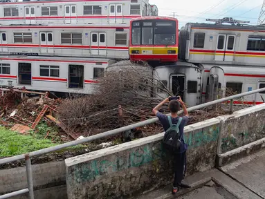 Seorang anak mengabadikan tumpukan Kereta Rel Listrik (KRL) afkir di Depo Depok, Jalan Kampung Rawageni, Cipayung, Kota Depok, Jawa Barat, Selasa (20/01/2026). 242 unit atau gerbong kereta yang sudah tidak terpakai dan ditumpuk di Depo Depok, Jalan Kampung Rawageni, Cipayung, Kota Depok, Jawa Barat. (Merdeka.com/Arie Basuki)