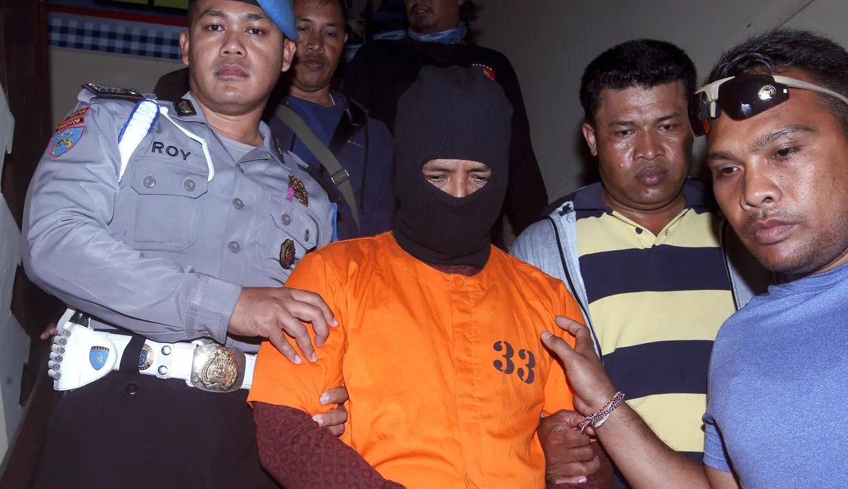 Petugas kepolisian mengawal tersangka kasus pembunuhan, Putu Astawa di kantor Polisi Bali, Denpasar (18/9). Astawa membunuh pasutri asal Jepang, Matshuba Hiroko yang berusia 70 tahun dan Matshuba Norio yang berusia 73. (AP Photo/Firdia Lisnawati)