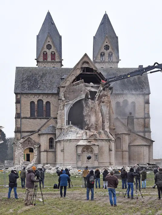 Warga dan sejumlah awak media melihat petugas dibantu alat berat membongkar Gereja St. Lambertus di Desa Immerath, Jerman (8/1). Pembongkaran dilakukan untuk perluasan pertambangan batubara, penghasil energi listrik. (AFP Photo/Henning Kaiser)
