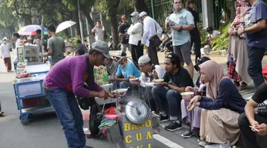 Pedagang asongan melayani pembeli yang mayoritas massa yang melakukan aksi di sekitaran Jalan Medan Merdeka Barat, Jakarta, Kamis (27/6/2019). Massa yang melakukan aksi terkait sidang putusan perselisihan hasil Pilpres 2019 memberi keuntungan bagi para pedagang. (Liputan6.com/Helmi Fithriansyah)