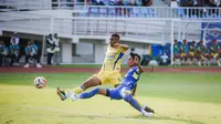 Bek kiri Arema FC, Johan Alfarizi menjuauhkan bola dari kejaran striker Persib Bandung, Uilliam Barros dalam laga pekan keenam BRI Super League 2025/2026 di Stadion Kanjuruhan, Kabupaten Malang, Senin (22/9/2025). (Bola.com/Iwan Setiawan).