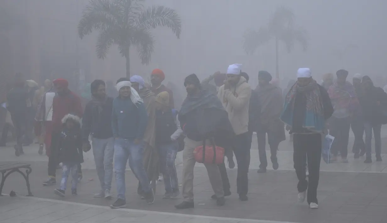 Orang-orang berjalan di sepanjang jalan Heritage di tengah kondisi berkabut pada Hari Tahun Baru, di Amritsar (1/1/2021). Sebagian besar India utara mencatat suhu yang menusuk tulang dan diselimuti kabut tebal sementara di Kashmir diselimuti salju pada Hari Tahun Baru. (AFP/Narinder Nanu)