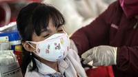 Seorang warga menerima vaksin virus corona COVID-19 Sinovac di pusat vaksinasi massal darurat di lapangan sepak bola di Surabaya, Jawa Timur, Kamis (30/9/2021). Vaksinasi ini dalam rangka percepatan penanganan COVID-19 dan pemulihan ekonomi nasional. (Juni Kriswanto/AFP)
