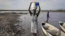 Seorang perempuan membawa air di kepalanya dari rawa, dengan sebagian besar daerah tidak memiliki akses ke air minum bersih karena banjir bertahun-tahun yang belum pernah terjadi sebelumnya, di Canal-Pigi County, Sudan Selatan pada 4 Mei 2023. (AP Photo/Sam Mednick)