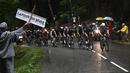 Rombongan pembalap melewati seorang penonton yang sedang memegang poster bertuliskan "Bumi itu datar" pada etape ke-8 balap sepeda Tour de France 2021 yang menempuh jarak 150 km, dari Oyonnax menuju Le Grand-Bornand, pada 03 Juli 2021. (AFP/Anne-Christine Poujoulat)