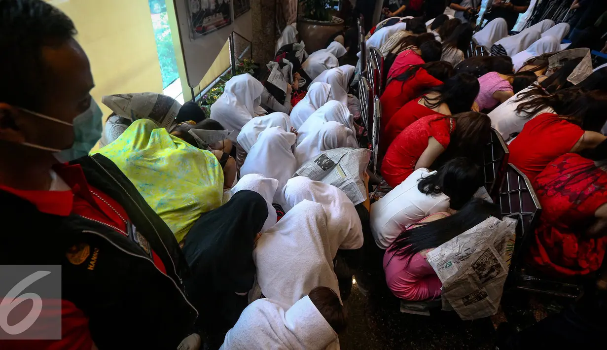Sejumlah WNA menutupi wajahnya saat diamankan di Direktorat Jenderal Imigrasi, Jakarta, Minggu (1/1). Sebanyak 76 WNA yang bekerja sebagai therapist pijat, pemandu lagu serta pekerja seks komersia (PSK) berhasil diamankan. (Liputan6.com/Faizal Fanani)