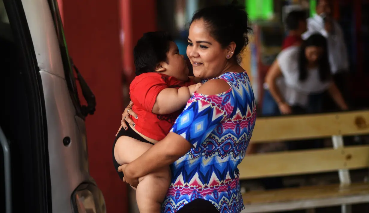 Isabel Pantoja  menggendong anaknya Luis Gonzales saat menunggu di stasiun bus di Tecoman, negara bagian Colima, Meksiko (9/11). (AFP Photo/Pedro Pardo)