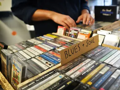 Giorgio Carbone, salah satu pendiri Mars Tapes memilih kaset di tokonya di Manchester, Inggris, 4 September 2021. Toko yang terselip pada sudut lantai atas pasar dalam ruangan di Manchester ini menjadi toko terakhir di Inggris yang didedikasikan untuk menjual kaset. (PAUL ELLIS/AFP)