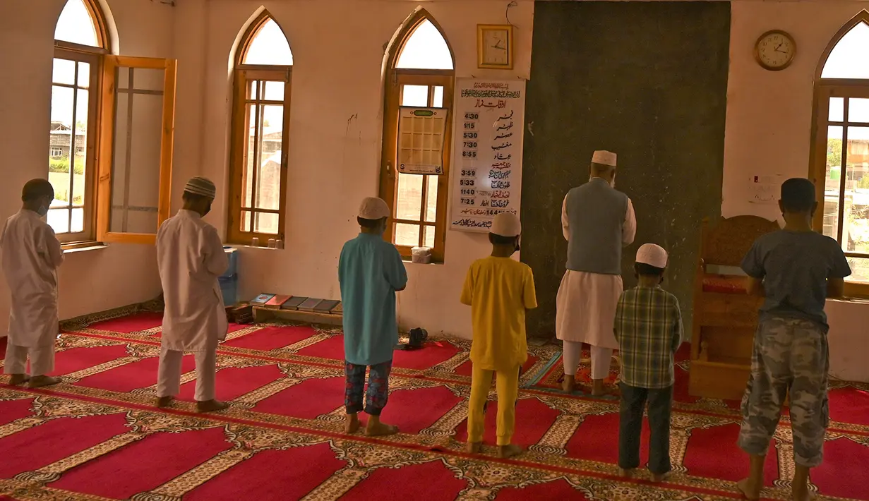 Anak-anak yatim Muslim mengenakan masker melaksanakan salat sambil menjaga jarak sosial di dalam pusat panti asuhan selama bulan suci Ramadan di Srinagar (11/5/2020). (AFP/Tauseff Mustafa)