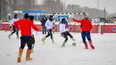 Para pemain berebut bola saat pertandingan persahabatan antara wartawan dan mahasiswa asing di lapangan bersalju di Nizhny Novgorod, Rusia, Minggu (21/1). Dalam pertandingan ini para pemain mengenakan sepatu tradisional Rusia. (AFP PHOTO/Mladen ANTONOV)
