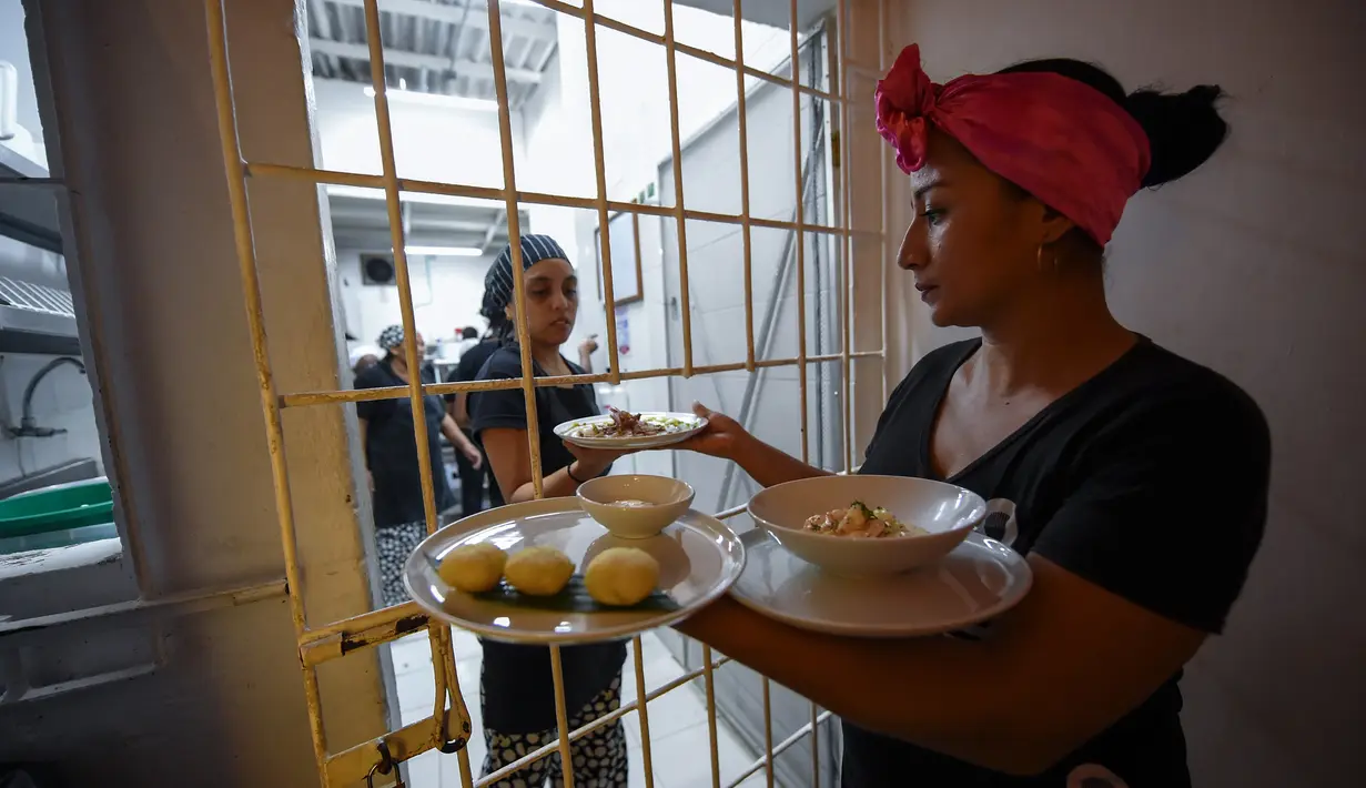 Dua narapidana wanita menyiapkan makanan saat bekerja di restoran Interno di Cartagena, Kolombia (24/8). Dengan adanya restoran ini narapidana wanita menerima pelatihan agar setelah bebas bisa diterima kembali oleh masyarakat. (AFP Photo/Raul Arboleda)
