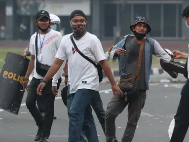 Polisi berpakaian kaus putih mengamankan seseorang yang dicurigai terlibat kericuhan di kawasan Tugu Tani, Jakarta, Selasa (13/10/2020). Sejumlah pemuda diamankan polisi karena dicurigai terlibat kericuhan di kawasan Tugu Tani. (Liputan6.com/Helmi Fithriansyah)