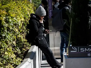 Seorang pria merokok di smoking area yang disediakan di Naka-Meguro, Tokyo (10/3). Kesadaran warga Jepang termasuk tinggi dengan tertibnya para perokok yang tidak merokok di sembarang tempat. (AFP Photo/BEHROUZ MEHRI)