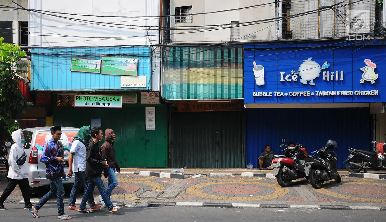 Pejalan kaki melintas di depan sejumlah pertokoan yang tutup di Jalan Sabang, Jakarta pada Rabu (22/5/2019). Pemilik toko dan pengelola kantor di kawasan tersebut menutup toko dan kantor mereka imbas aksi 22 Mei 2019 yang berakhir rusuh di beberapa titik lokasi. (Liputan6.com/Aangga Yuniar)
