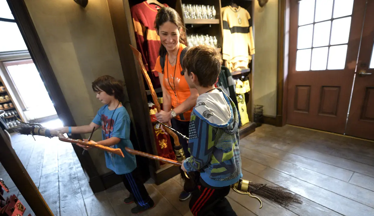 Dove Rudman bersama anak-anaknya mencoba sapu terbang di toko Dervish and Banges saat soft opening dan tur media taman bermain "The Wizarding World of Harry Potter" di Universal Studios Hollywood, California, 22 Maret 2016. (REUTERS/Kevork Djansezian)