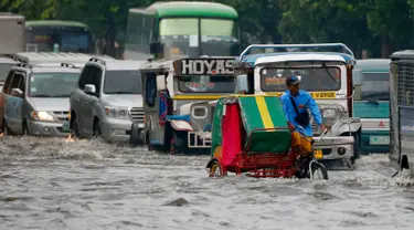 Pengendara becak menerjang genangan air di salah satu wilayah Manila, Filipina, Kamis (27/7). Banjir menggenangi beberapa wilayah Kota Metropolitan setelah hujan lebat yang diakibatkan oleh badai tropis ‘Nesat’. (AP/Bullit Marquez)