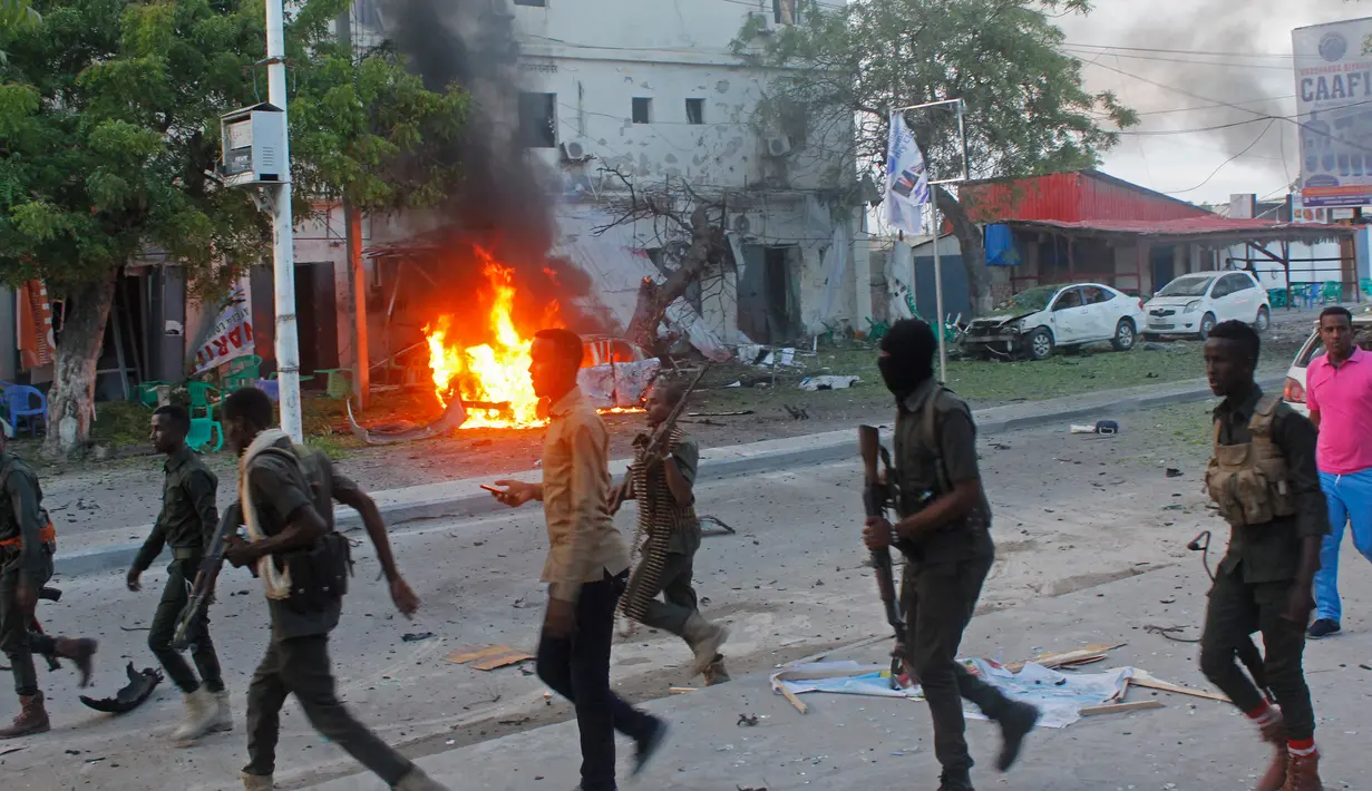 Petugas berjalan di dekat mobil yang terbakar setelah sebuah serangan bom mobil di sebuah restoran di Mogadishu, Somalia, (8/5). Setidaknya 6 orang tewas dan 10 orang lainnya terluka dalam serangan bom mobil tersebut. (AP Photo/Farah Abdi Warsameh)