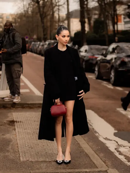 Alyssa Daguise dalam balutan outfit serba hitam. Pesonanya tak main-main dibalut mini dress hitam, yang ditumpuknya dengan long coat yang juga berwarna hitam, kitten heels hitam, dan mini bag yang ditentengnya berwarna cokelat bata. [Foto: Instagram/alyssadaguise]