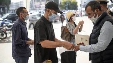 Orang-orang menunjukkan paspor vaksin sebelum diizinkan masuk memasuki kantor pemerintah, di Rabat, Maroko, Kamis (21/10/2021). Maroko mewajibkan paspor vaksin untuk mengakses kantor pemerintah, mal, pusat kebugaran, dan area publik lain untuk mendorong kampany vaksinasi. (AP Photo/Mosa'ab Elshamy)