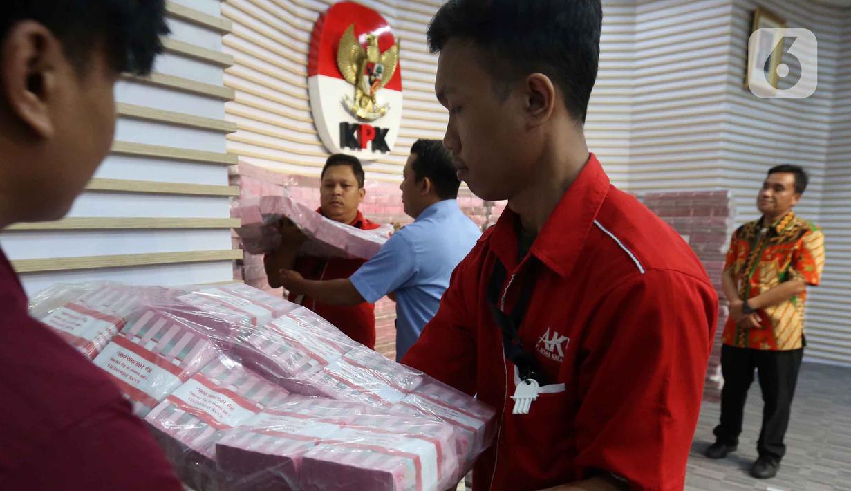 Petugas mengangkut uang dari tumpukan sebesar Rp 300 miliar yang dipamerkan di gedung Merah Putih Komisi Pemberantasan Korupsi (KPK), Jakarta, Kamis (20/11/2025). (Liputan6.com/Helmi Fithriansyah)