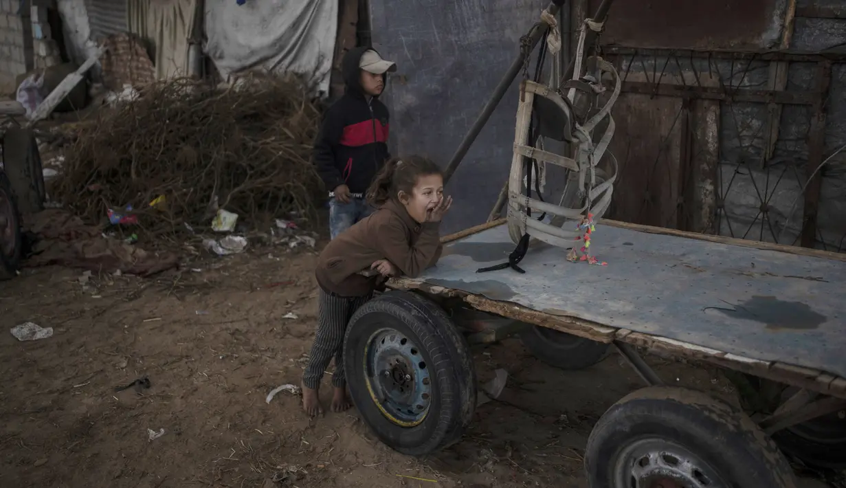 Anak-anak Palestina bermain di luar rumah mereka saat cuaca dingin di daerah kumuh di pinggiran kamp pengungsi Khan Younis, Jalur Gaza selatan pada Rabu, 19 Januari 2022. (AP Photo/Khalil Hamra)