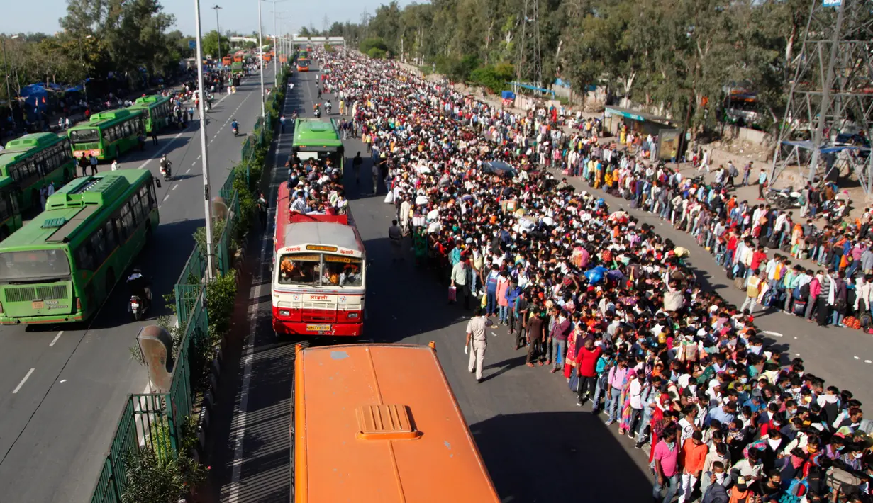 Buruh migran India menunggu bus untuk mengangkut mereka menuju kampung halaman setelah pemberlakukan lockdown di New Delhi, Sabtu (28/3/2020). Arus eksodus massal ini terjadi beberapa jam setelah otoritas setempat mengumumkan menyediakan ratusan bus bagi yang ingin meninggalkan Delhi. (AP Photo)