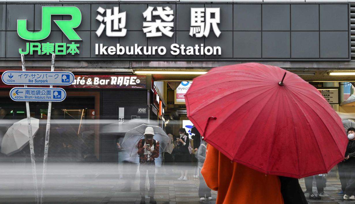 Yamanote Line memiliki panjang 35,9 kilometer atau sekitar 22 mil lebih. Foto yang diambil pada tanggal 18 Juni 2024 ini menunjukkan orang-orang yang menggunakan payung untuk melindungi diri dari hujan di luar stasiun Ikebukuro, salah satu dari 30 stasiun di sepanjang Jalur JR Yamanote di Tokyo. (Richard A. Brooks/AFP)
