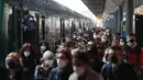 Para penumpang yang mengenakan masker berjalan di peron setelah turun dari kereta regional di stasiun Cadorna di Milan, Senin (26/4/2021). Italia kembali dibuka secara bertahap pada hari Senin setelah enam bulan memberlakukan lockdown untuk menghambat penyebaran Covid-19. (AP Photo/Antonio Calanni)