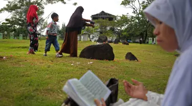 Anggota keluarga menabur bunga di salah satu makam korban tsunami Aceh di sebuah kuburan massal di Aceh, Senin (26/12). Warga Aceh memperingati 12 tahun gempa dahsyat berkekuatan 9,3 SR disusul tsunami pada Minggu 26 Desember 2004 (CHAIDEER MAHYUDDIN/AFP)