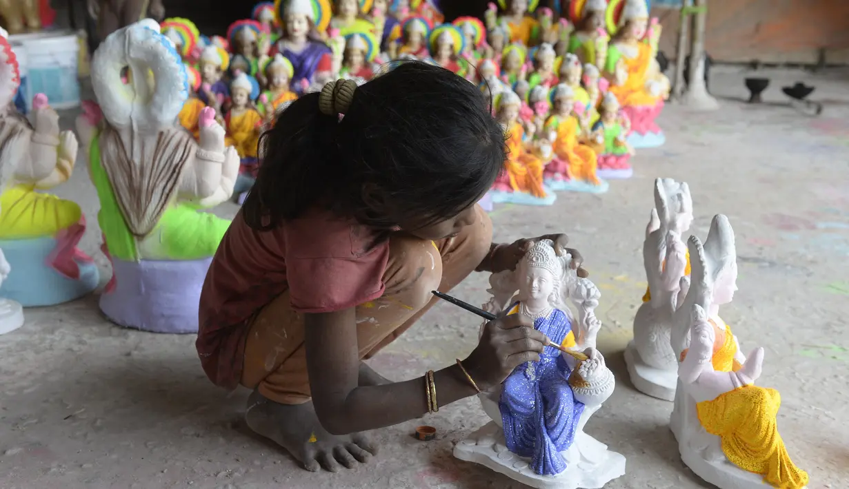 Seorang seniman muda melukis patung dewi Hindu Lakshmi di sebuah bengkel menjelang Diwali, festival lampu Hindu di pinggiran Hyderabad (28/10/2021). Diwali, festival lampu, dirayakan pada 4 November. (AFP/Noah Seelam)