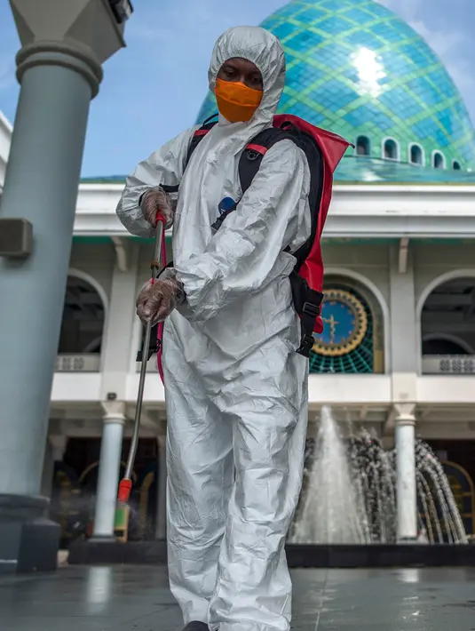Pekerja dari otoritas penanggulangan bencana setempat menyemprotkan desinfektan di sebuah masjid di Surabaya, Jawa Timur, Selasa (17/3/2020). Kegiatan tersebut dilakukan untuk mencegah penyebaran Virus Corona COVID-19. (Photo by Juni Kriswanto / AFP)