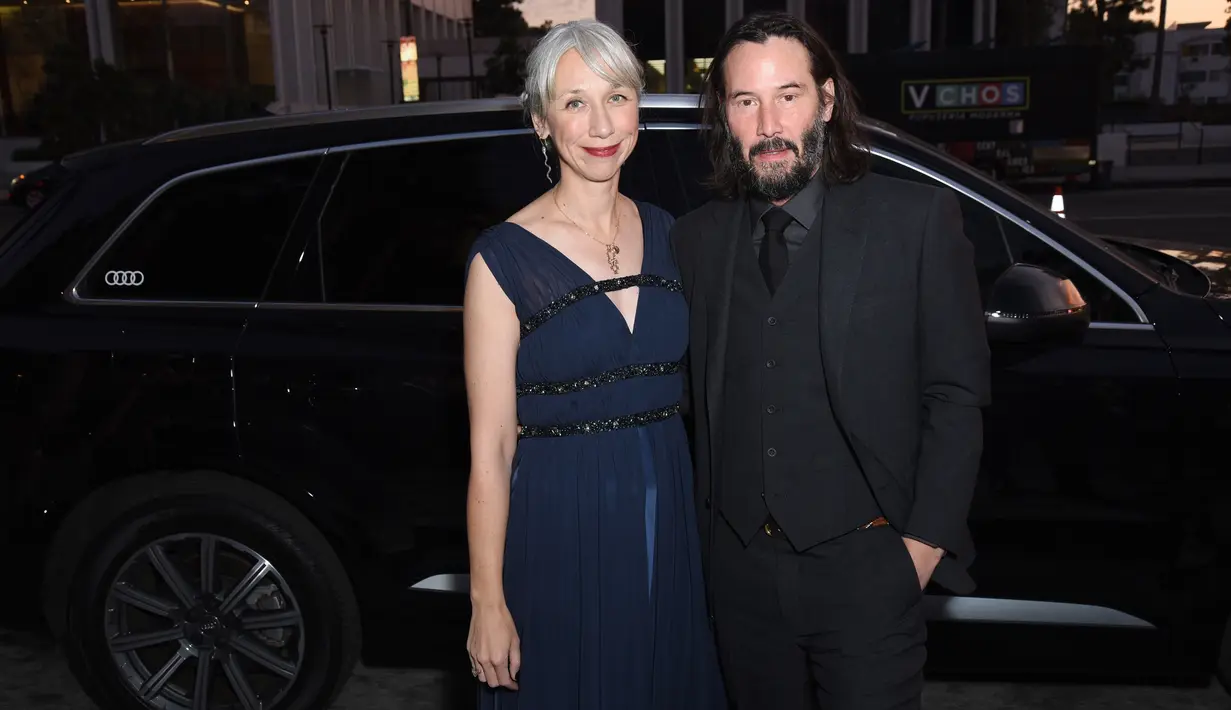 Aktor Keanu Reeves bersama Alexandra Grant menghadiri  LACMA Art + Film di Los Angeles, 2 November 2019. Keanu Reeves mengenakan setelas jas berwarna hitam, sedangkan sang kekasih mengenakan gaun biru tua dnegan potongan kerah bentuk V. (Presley Ann/Getty Images for Audi/AFP)