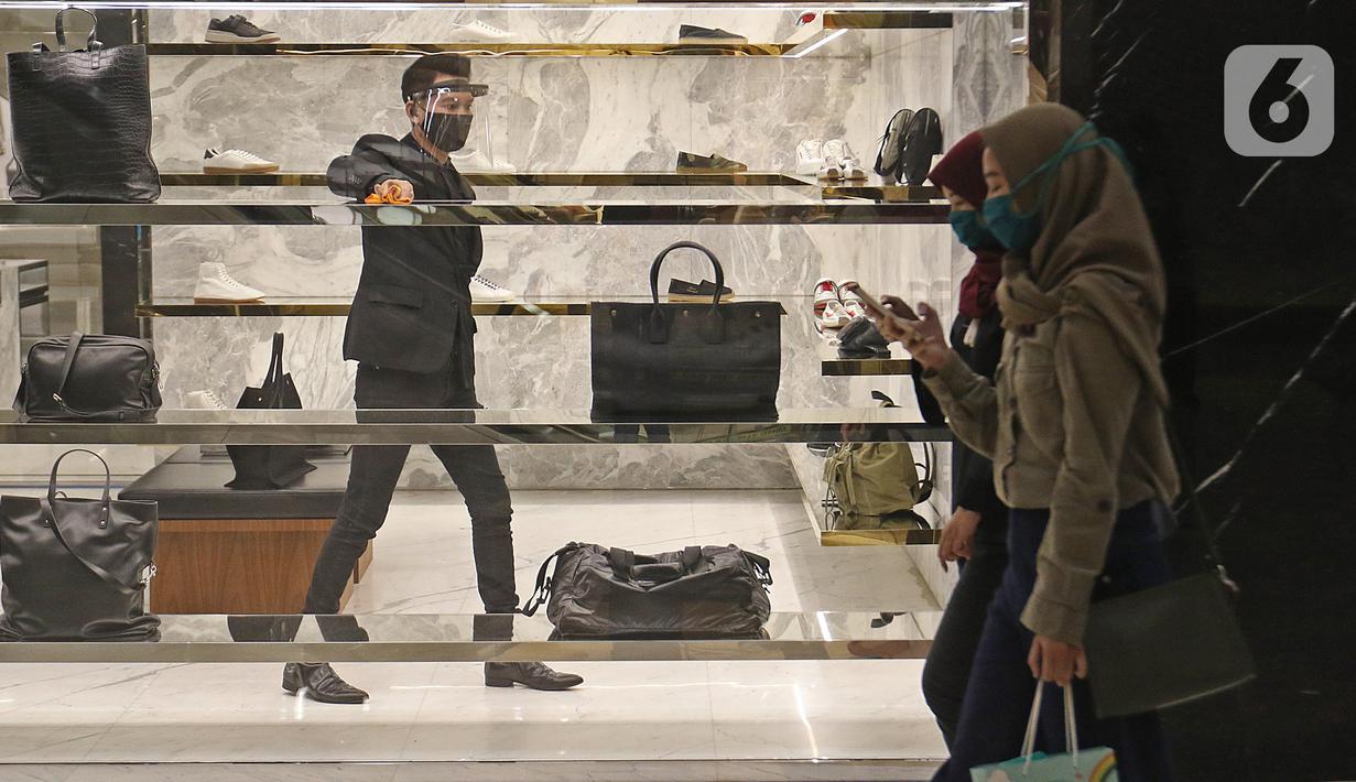 Pengunjung melintas saat pekerja membersihkan salah satu gerai di Mall Senayan City, Jakarta, Senin (15/6/2020). Pusat perbelanjaan atau mal di Jakarta kembali dibuka pada Senin (15/6) di masa PSBB transisi dengan jumlah pengunjung masih dibatasi hanya 50 persen. (Liputan6.com/Herman Zakharia)